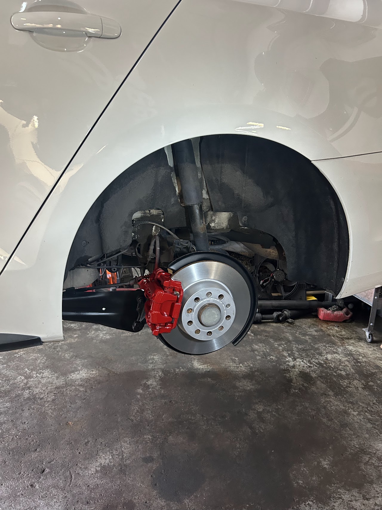Close-up shot of technician replacing precision disc brake rotor and caliper on a car wheel assembly in clean auto workshop, glowing amber light, photorealistic detailed automotive repair photography